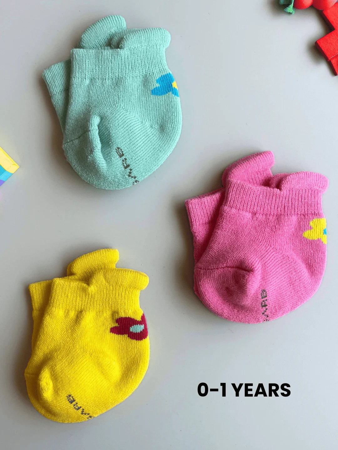 Air Garb infant combo socks featuring a flower design for babies 0-1 years; a 3-pair collection of high-quality cotton socks in mint green, vibrant yellow, and bright pink.